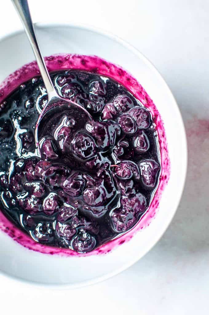blueberry compote in a white bowl with a silver spoon