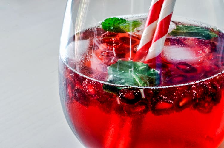 A Shirley Temple drink with pomegranate seeds and mint.
