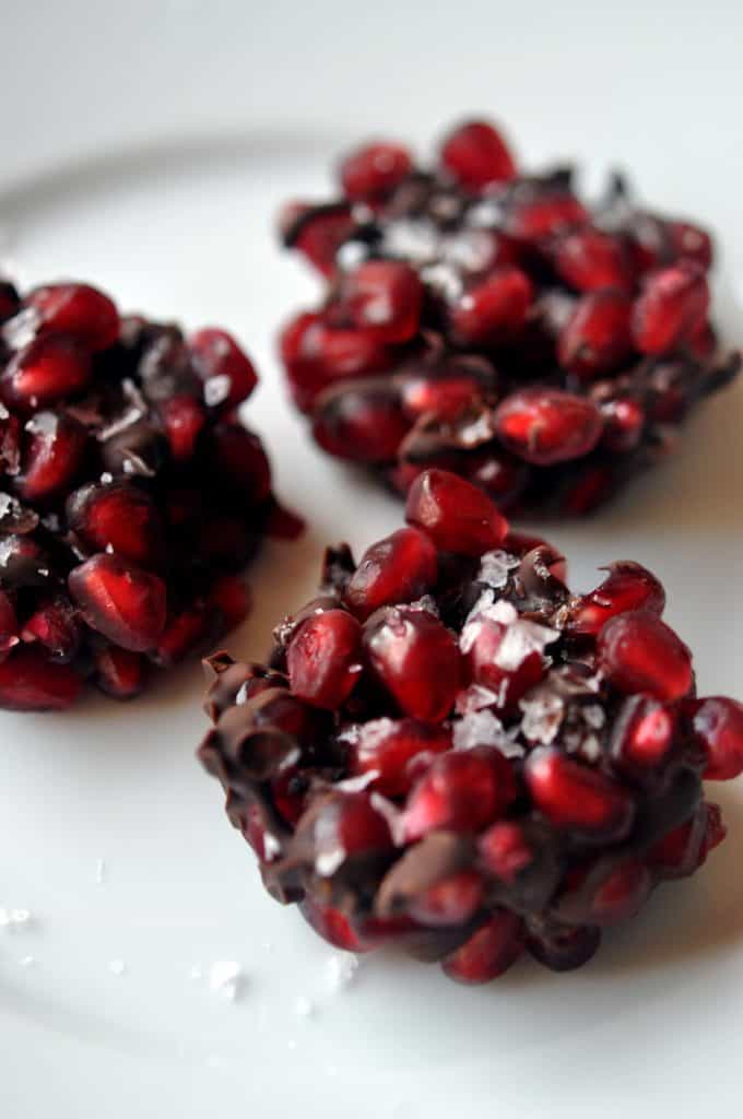 three pomegranate dark chocolate bites on a white background