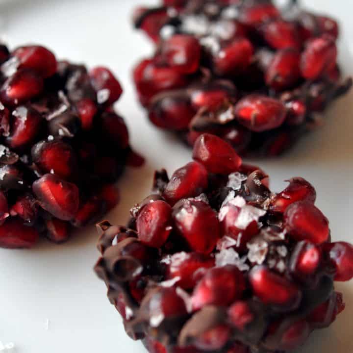 three pomegranate dark chocolate bites on a white background