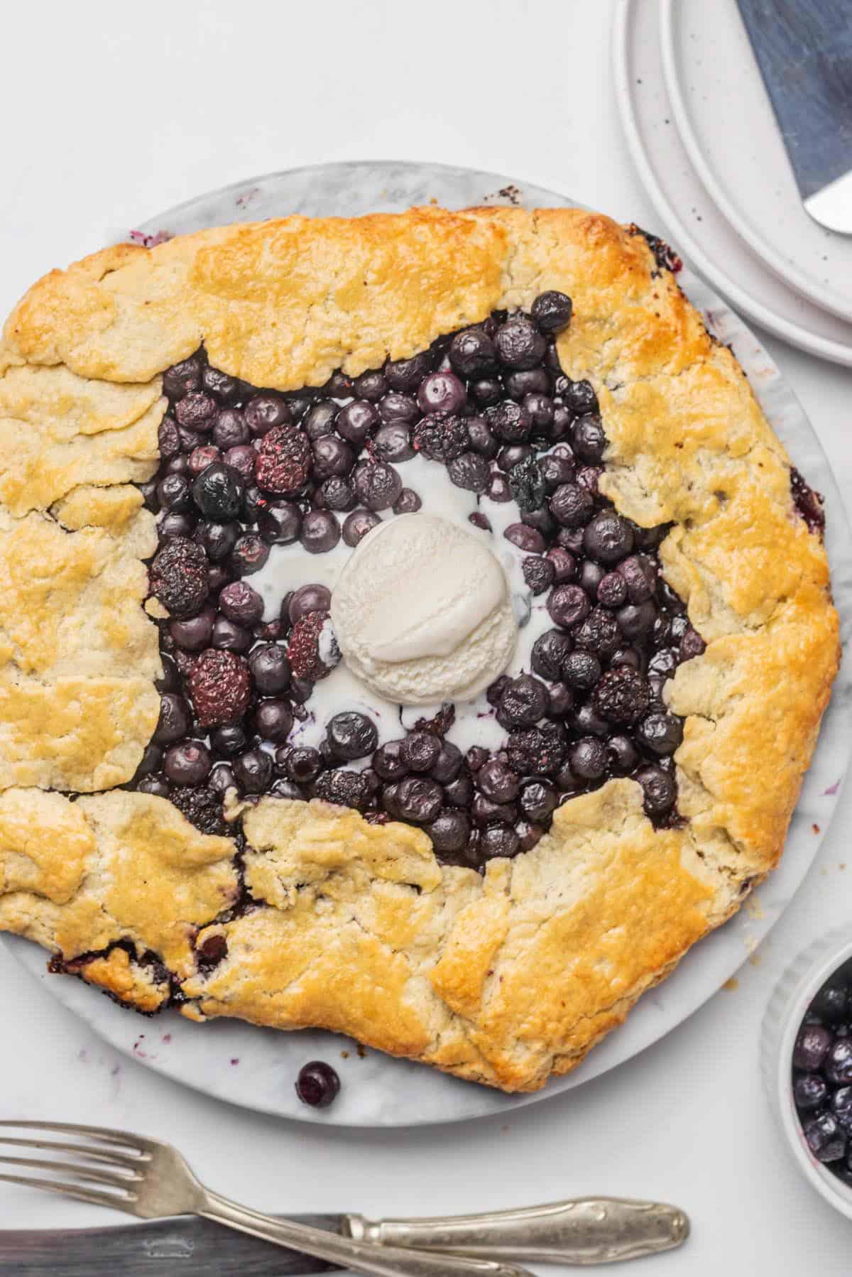 A blueberry blackberry galette with a scoop of vanilla ice cream.