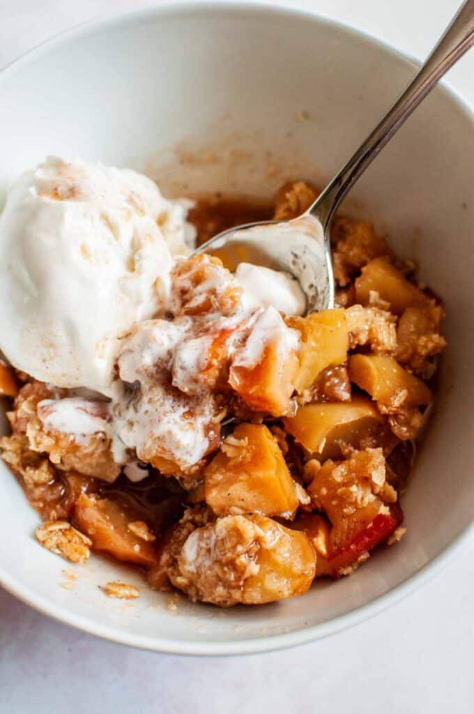 apple crisp in a bowl with vanilla ice cream