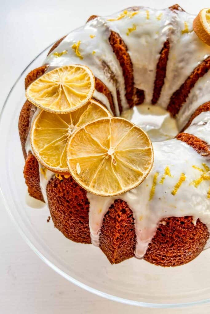 orange bundt cake with glaze on a glass cake plate