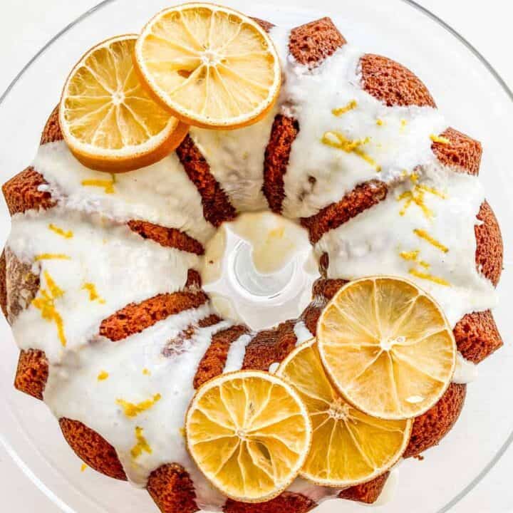 Mandarin orange bunt cake with frosting drizzle on a glass plate.