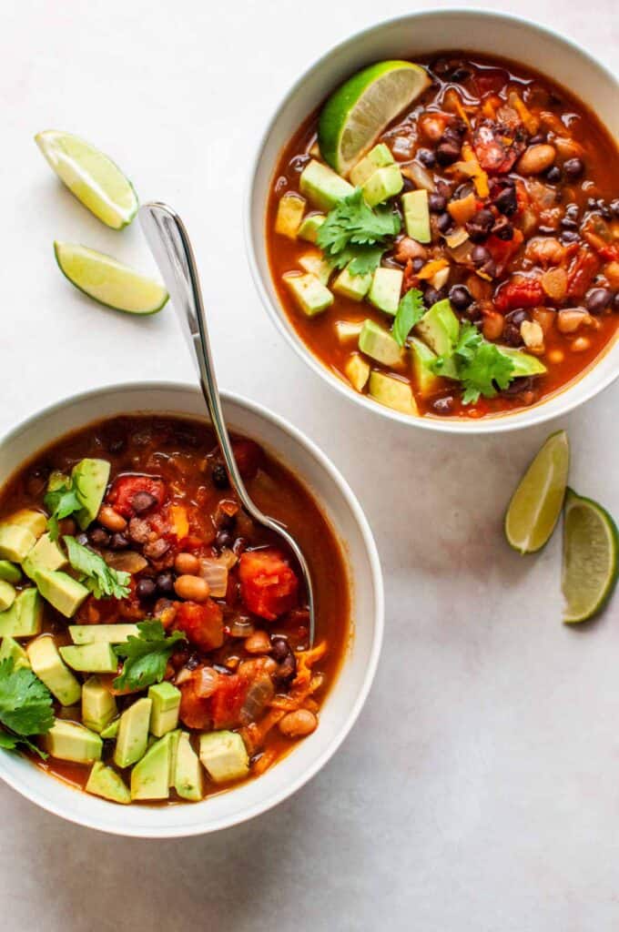 Two bowls of vegan chili with diced avocados.