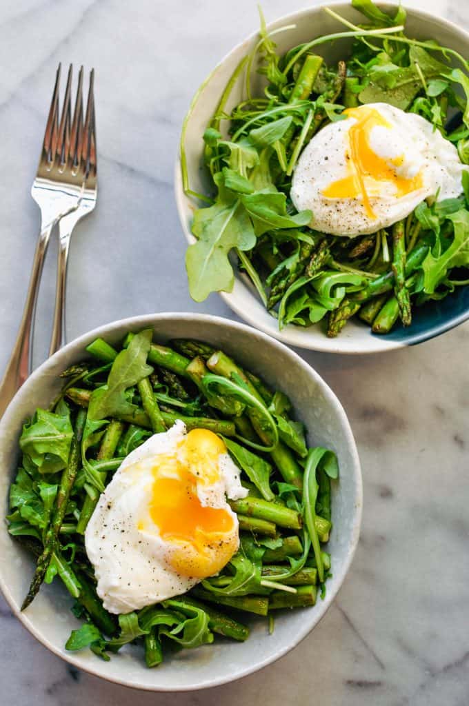 arugula and asparagus in a bowl with poached egg