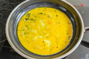 Eggs cooking for an omelet in a frying pan.