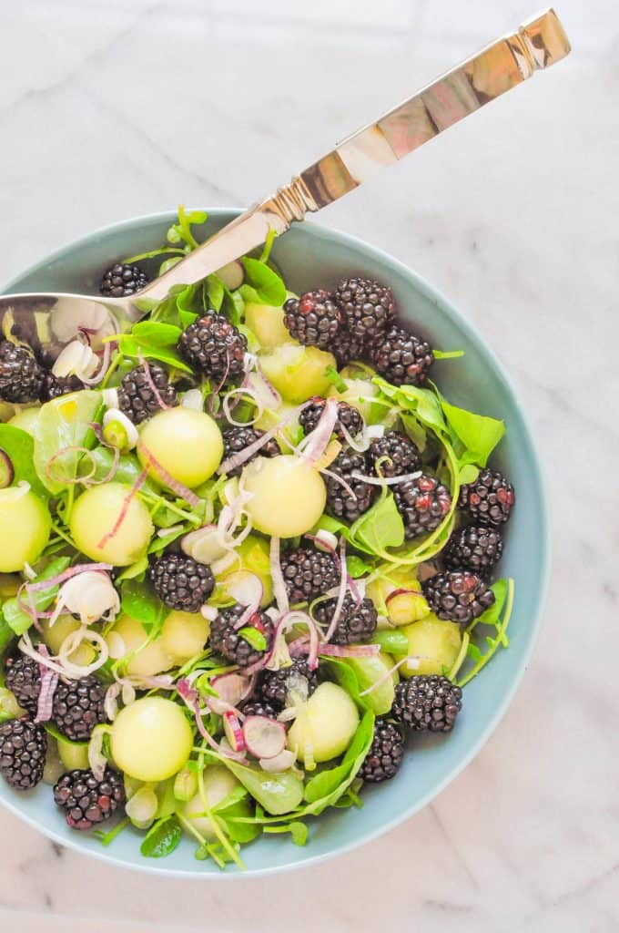 honeydew salad with blackberries in a blue serving bowl