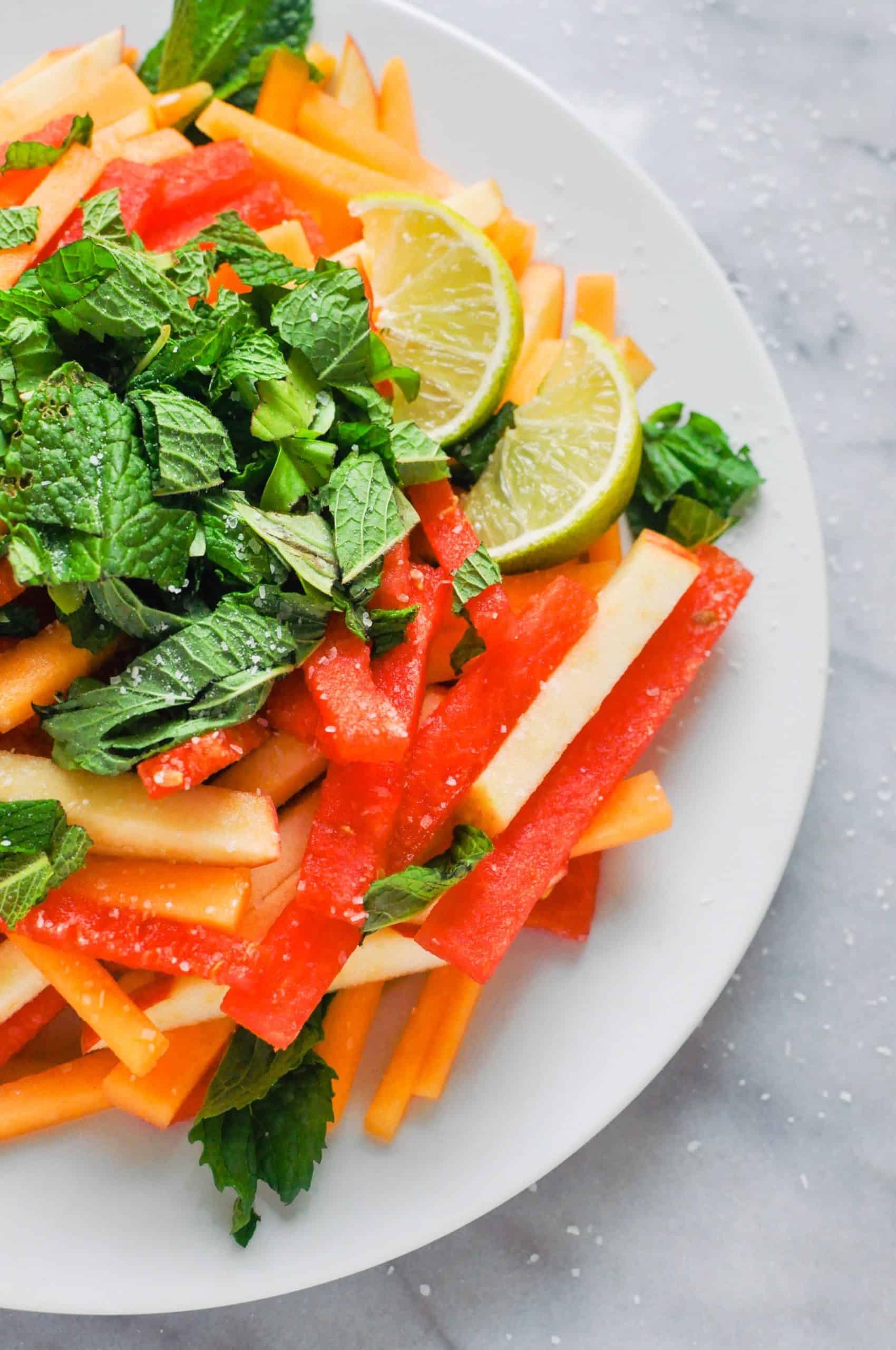 A watermelon, apple, cantaloupe summer salad on a white plate.