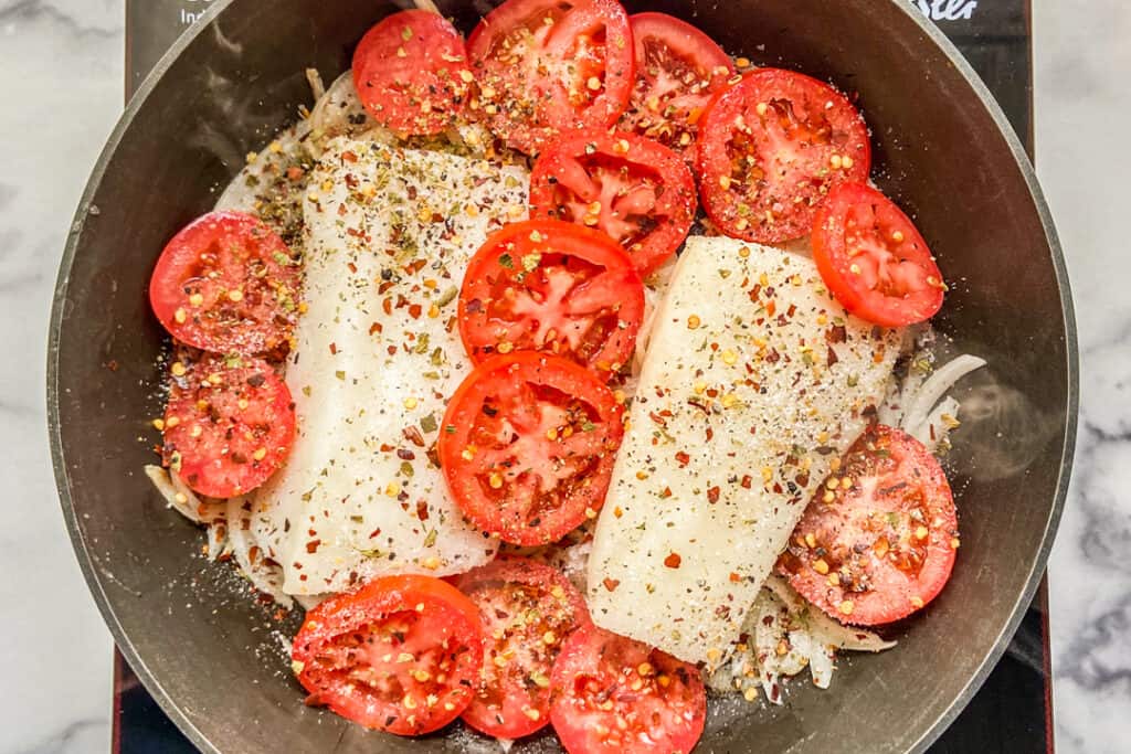 Sea bass and tomatoes in a skillet.