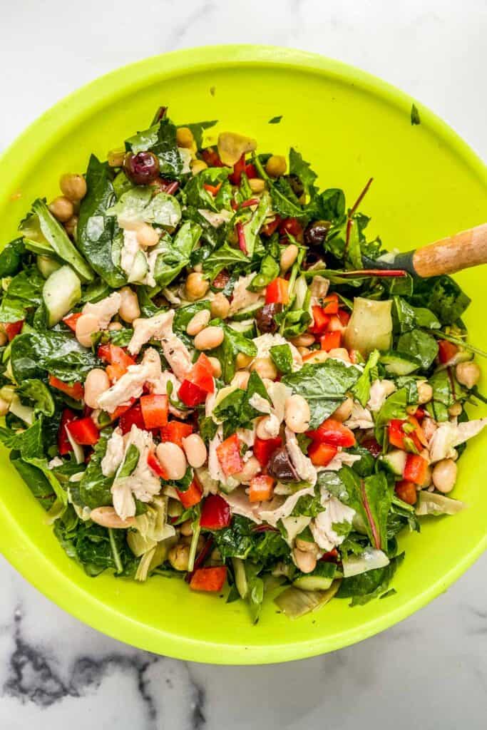 An overhead shot of a green mixing bowl with chicken salad.