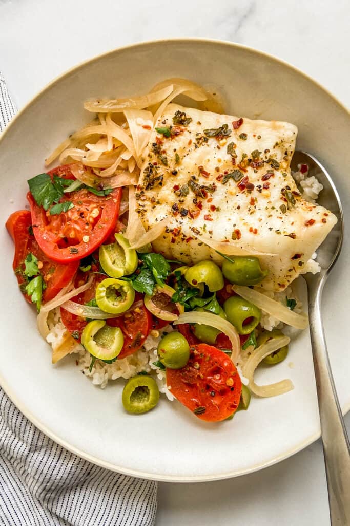 Poached sea bass with vegetables and rice in a bowl.