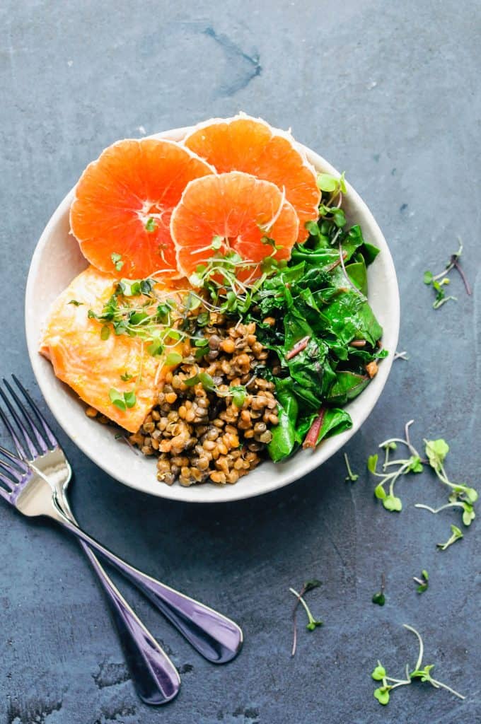 oranges, salmon, greens, lentils in a bowl