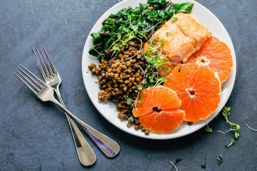 oranges, salmon, lentils, and greens in a bowl