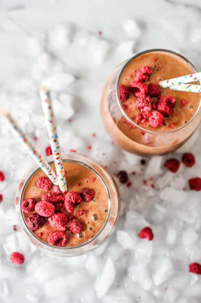 zwei Gläser veganer Schokoladenshake mit gefriergetrockneten Himbeeren