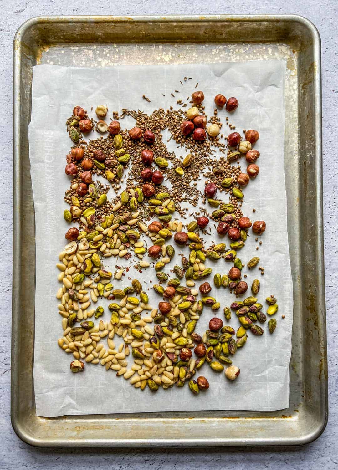 Ingredients for dukkah on a parchment lined sheet pan.
