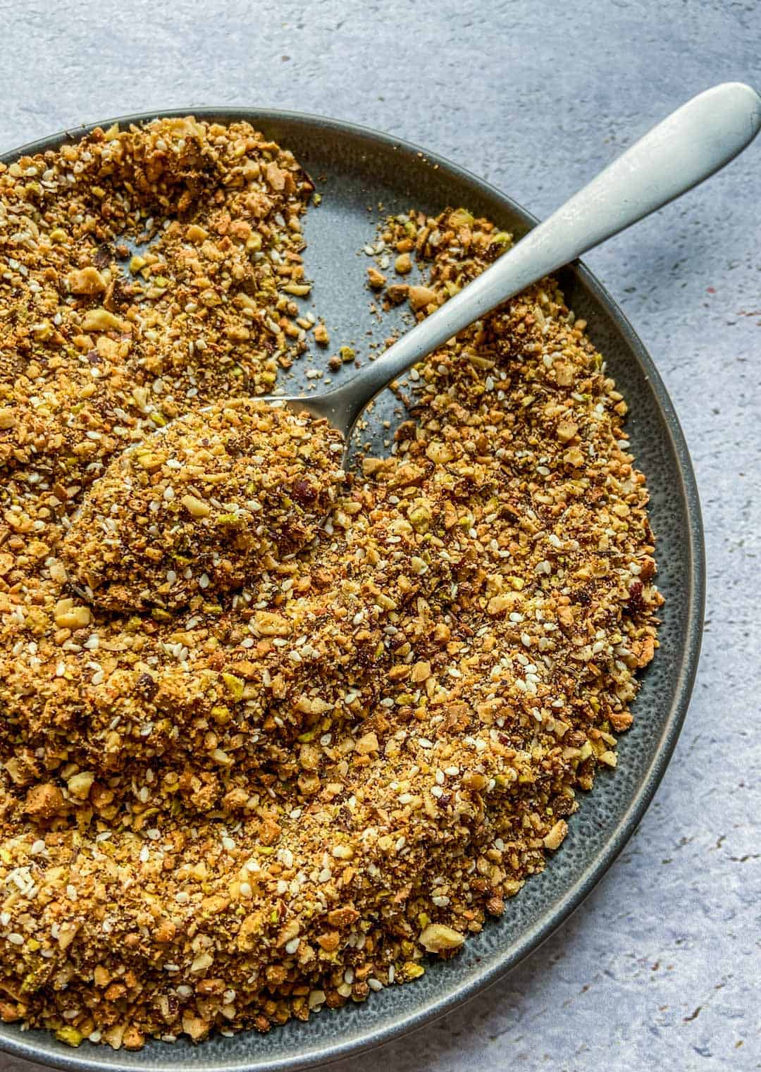 Dukkah spice in a metal plate with a spoon.