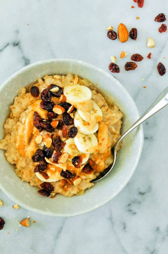 bowl of slow cooker peanut butter oatmeal topped with bananas and dried fruit