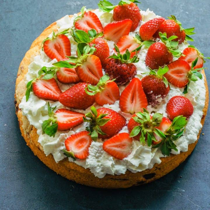 Strawberry tahini cake with strawberries and whip cream on top.