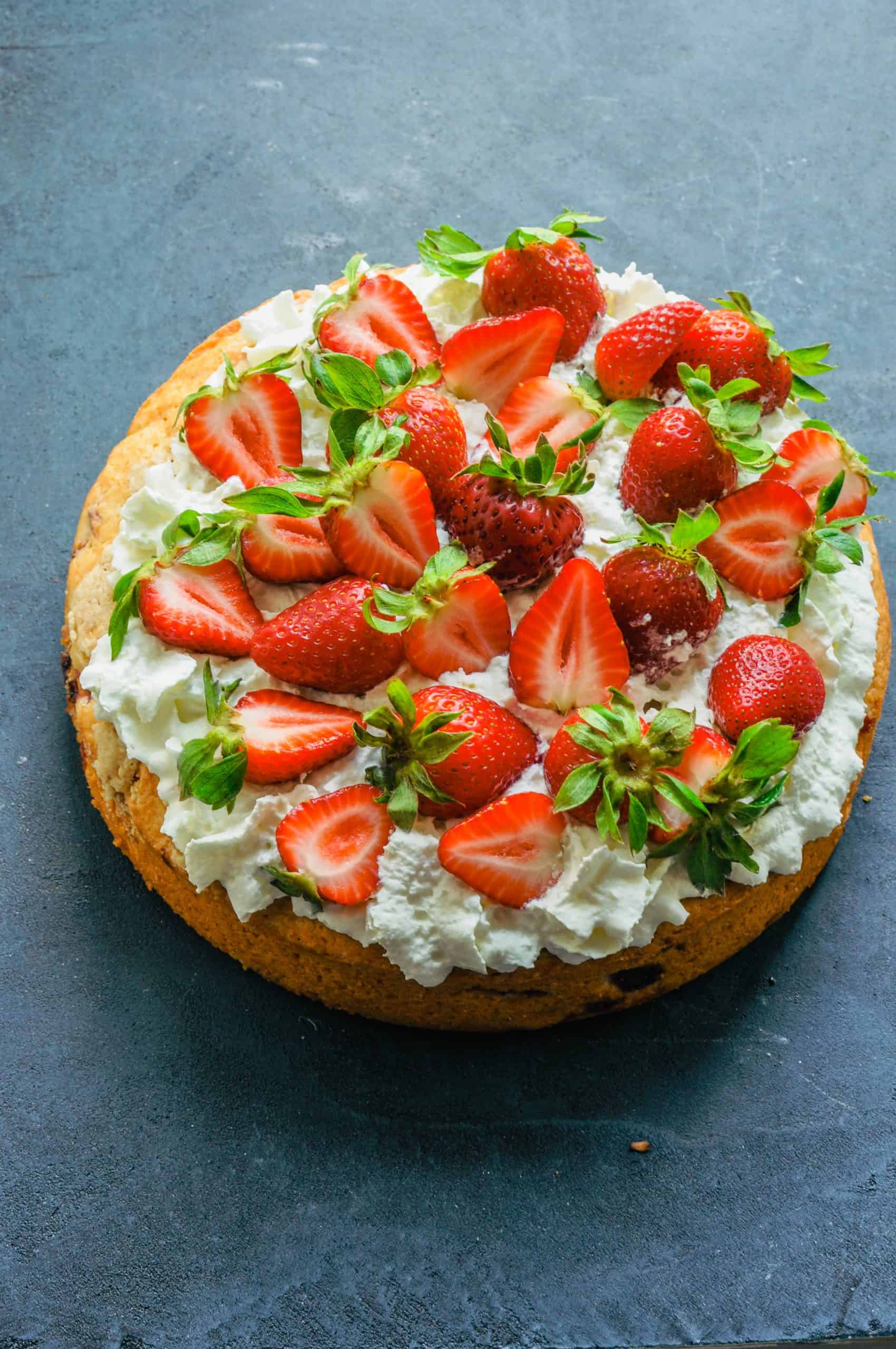 Strawberry tahini cake with strawberries and whip cream on top.