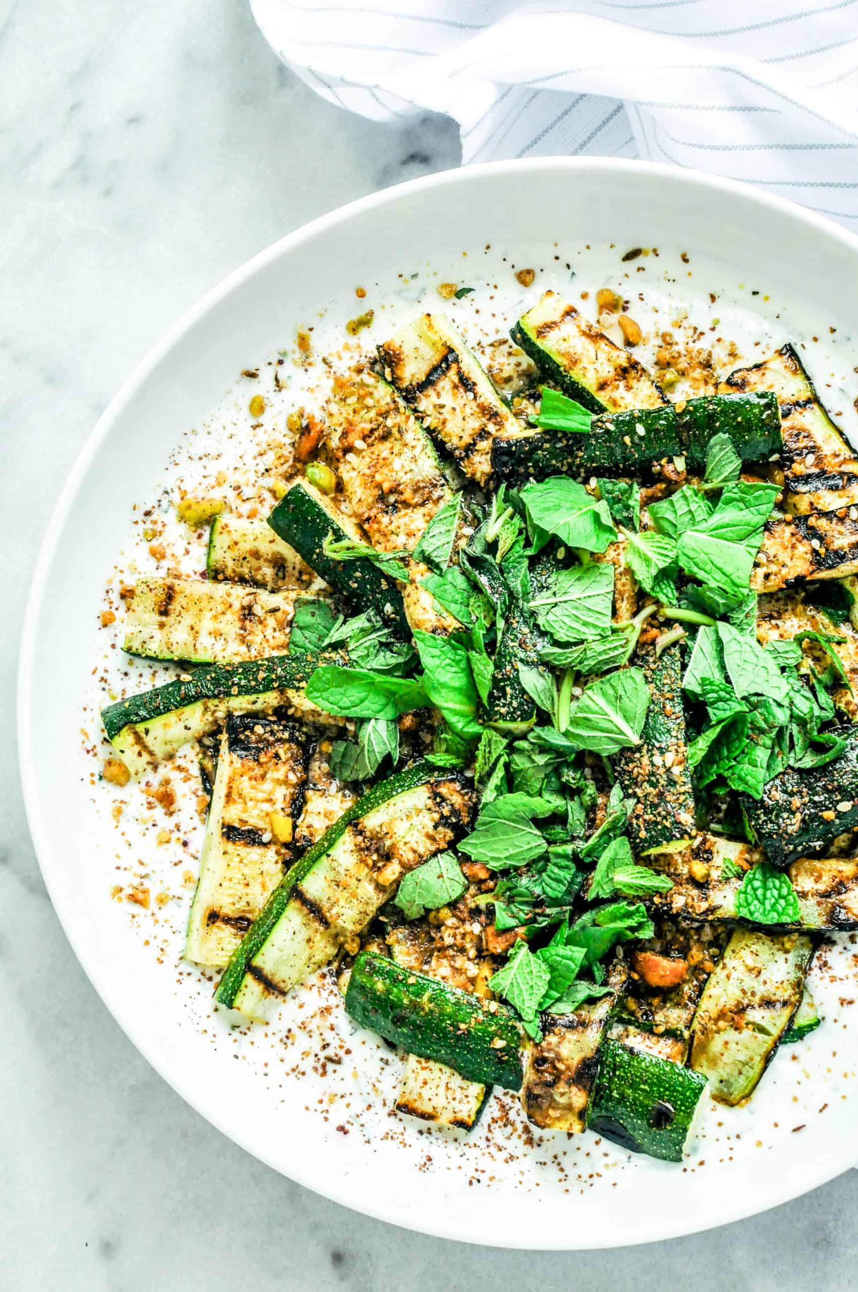 Grilled zucchini with yogurt, Dukkah, and Sumac with basil on top.