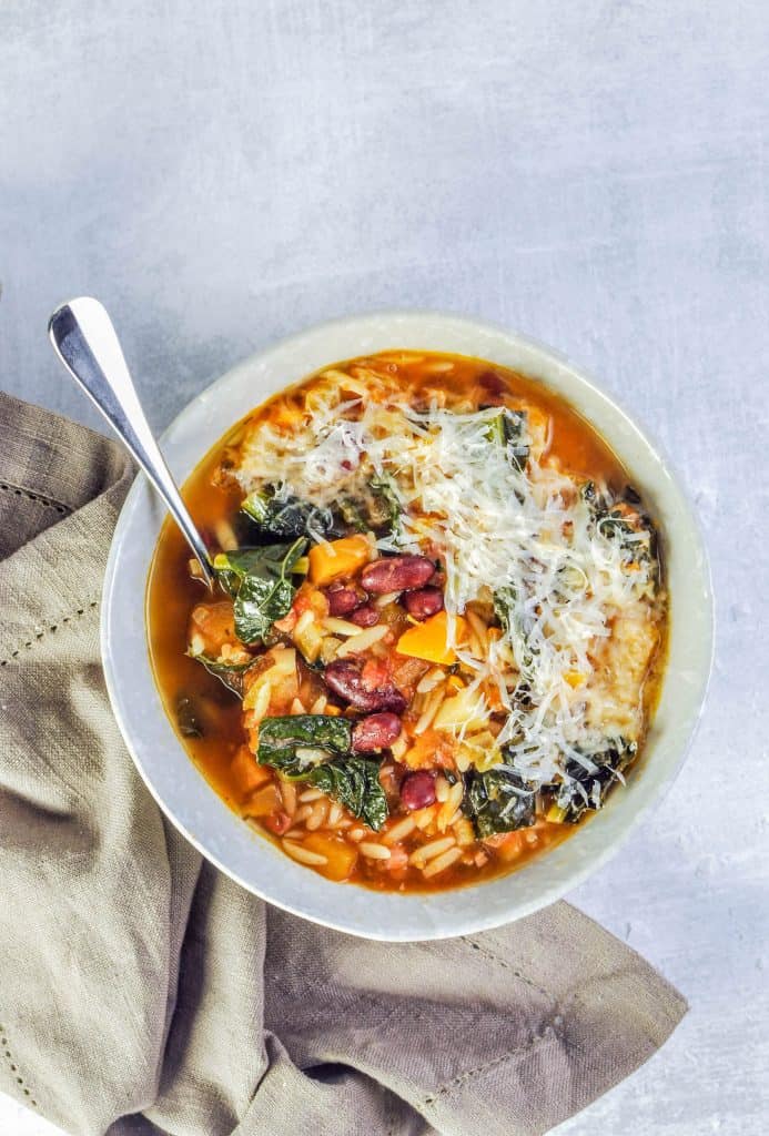 pumpkin minestrone soup in a bowl next to a napkin