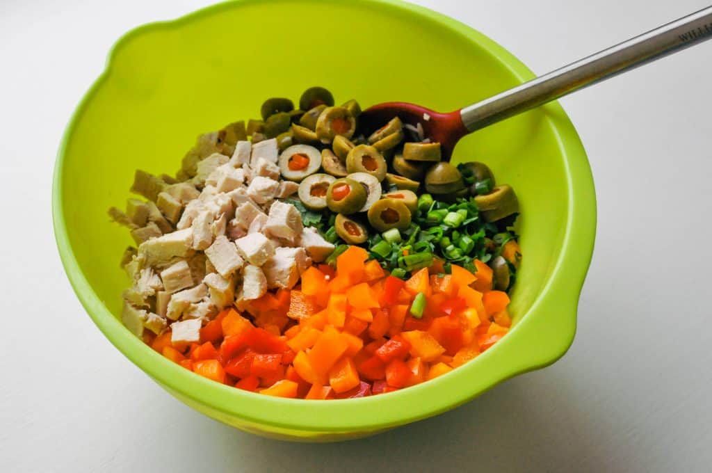 chicken orzo salad ingredients in a mixing bowl with a spoon