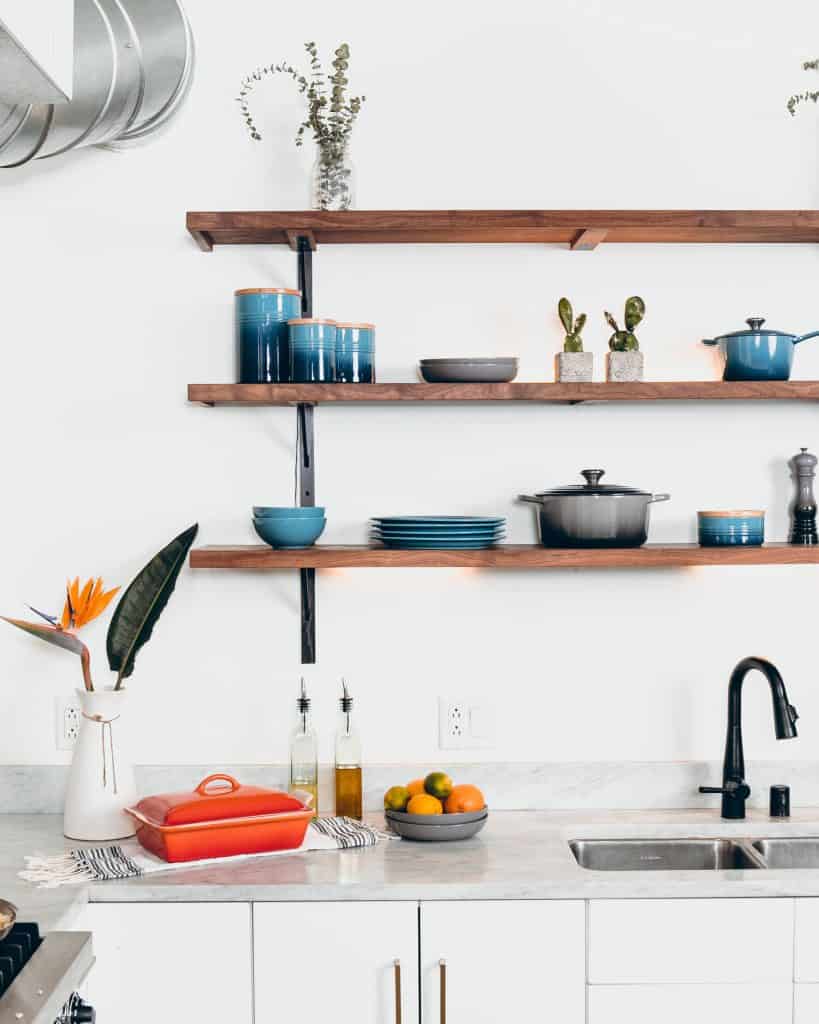 Cookware in a white kitchen with open shelves.