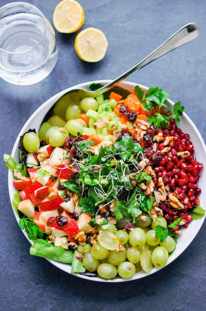 grapes, apples, pomegranate, and microgreens in a bowl