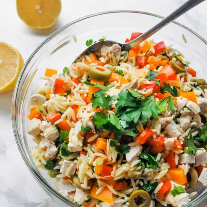 Orzo and chicken salad in a large glass mixing bowl.