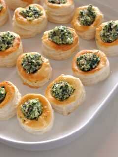 Spinach and feta puff pastry bites lined up on a serving plate.