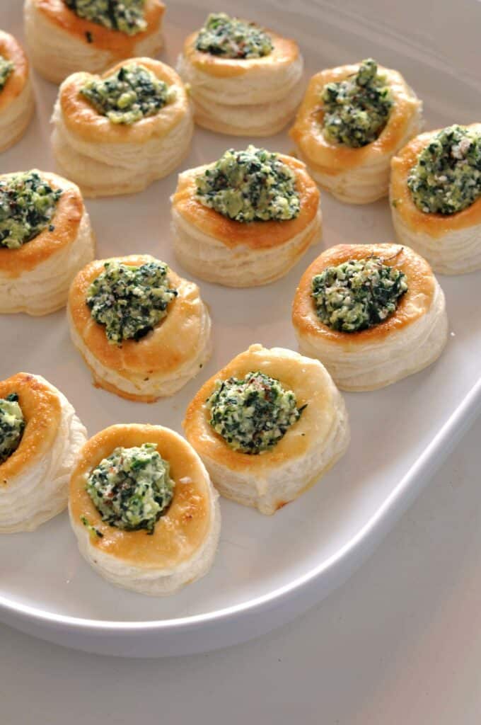 Spinach and feta puff pastry bites lined up on a serving plate.