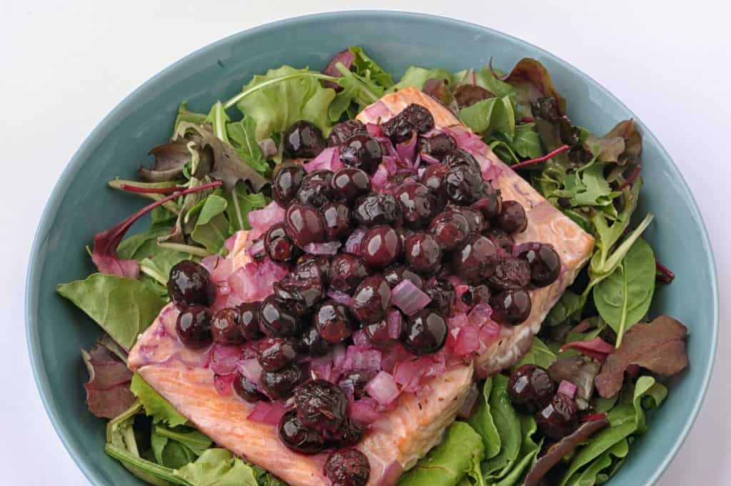 salmon and blueberries on a plate with greens