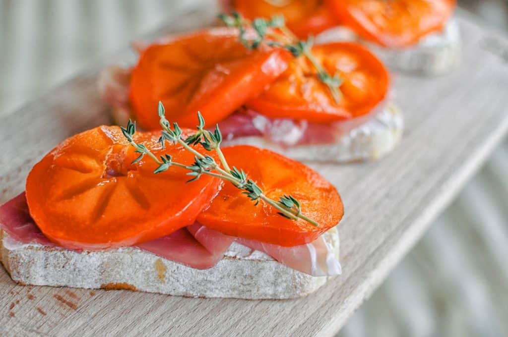 persimmon prosciutto crostinis on a cutting board