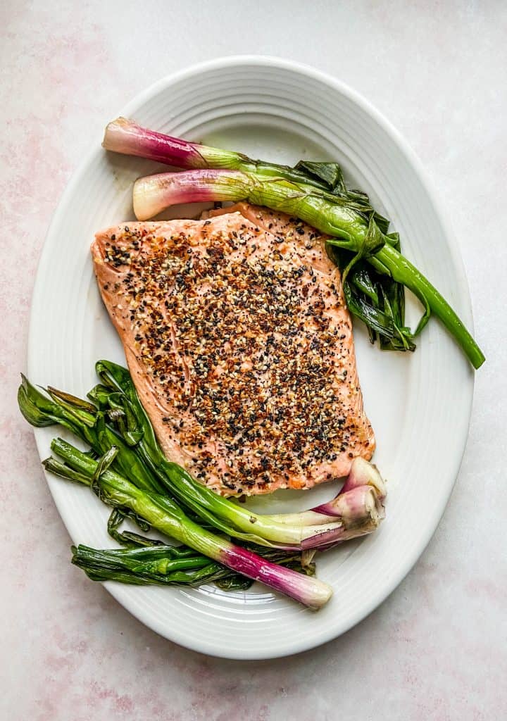 sesame salmon with roasted spring onions on a white platter