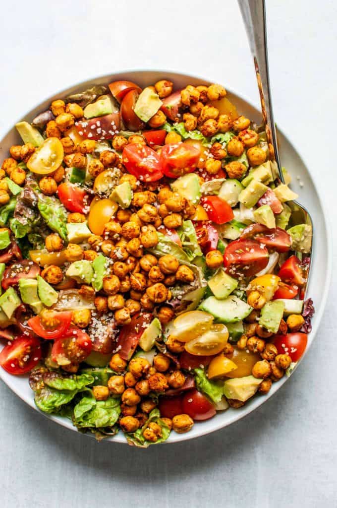 roasted chickpea salad in a large serving bowl with a silver spoon