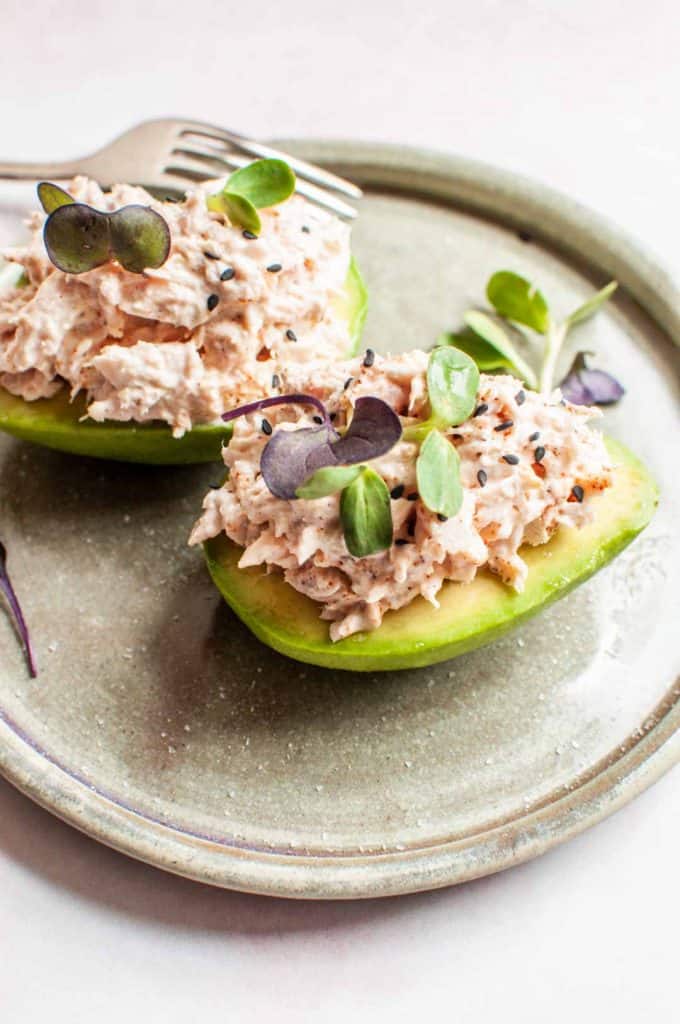 side shot of two tuna stuffed avocados on a plate