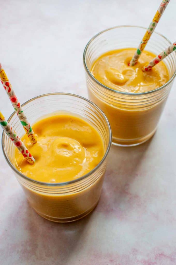 mango lassi in two glasses with paper straws