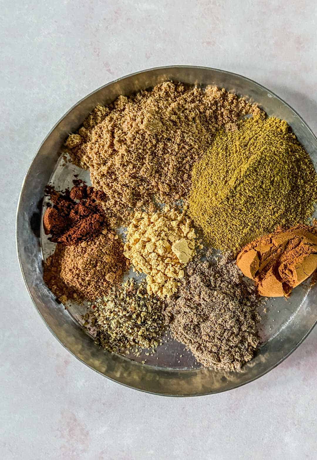 A metal bowl with spices for garam masala.