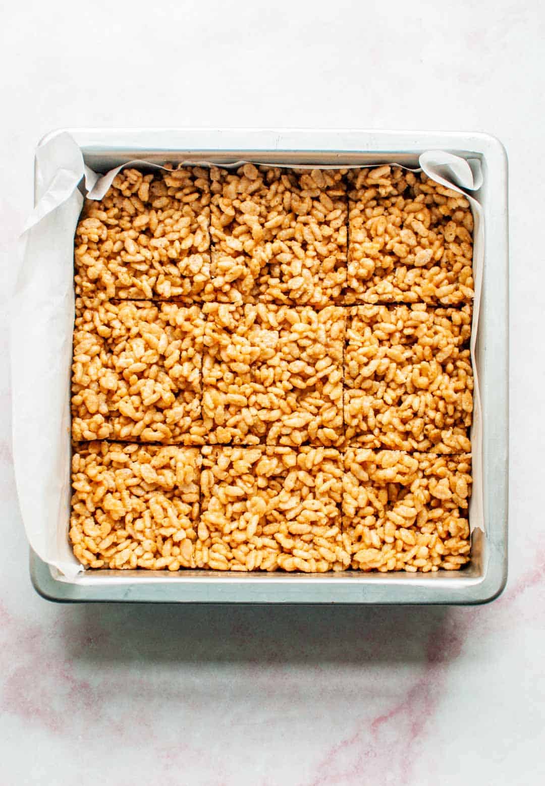 Peanut butter rice krispie treats in a pan cut into nine pieces.