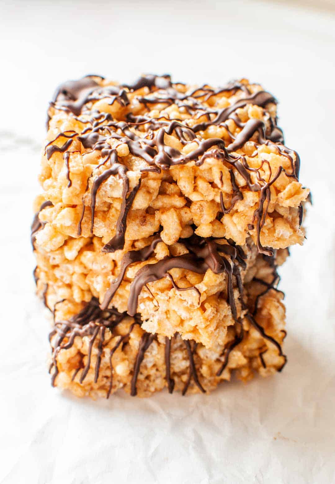 Three pieces of peanut butter rice krispie treats with chocolate drizzle in a stack.