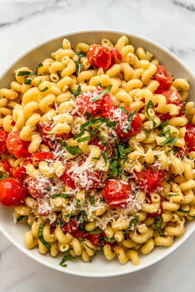 Burst cherry tomato pasta in a large, white serving bowl.