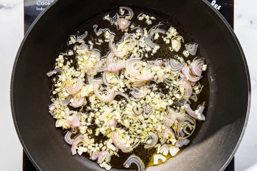 Shallots and garlic cooking in oil.