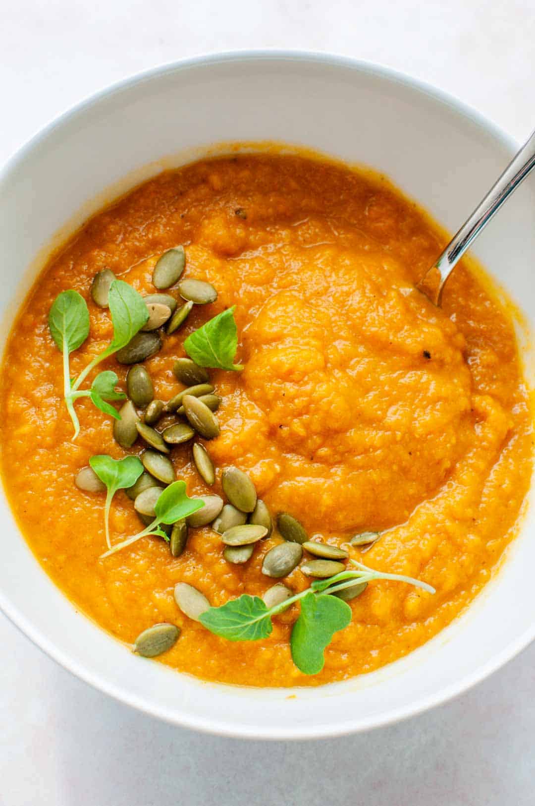 Butternut squash soup in a white bowl topped with pepitas.