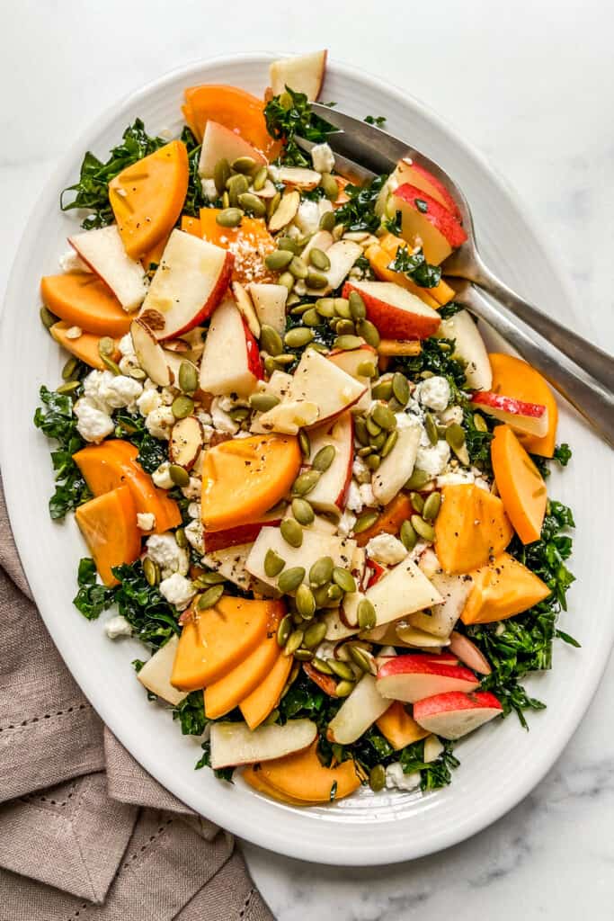 A large persimmon salad on a white platter.