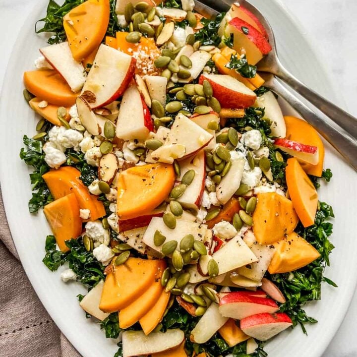 A large persimmon salad on a white platter.