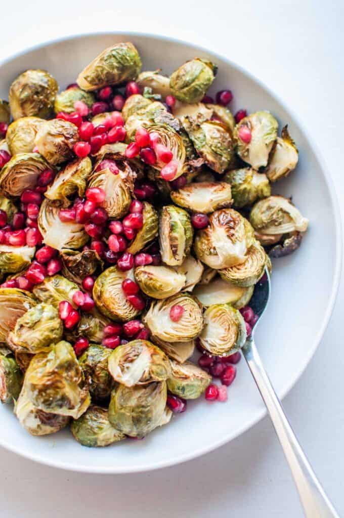 roasted brussels sprouts with pomegranate seeds in a serving bowl