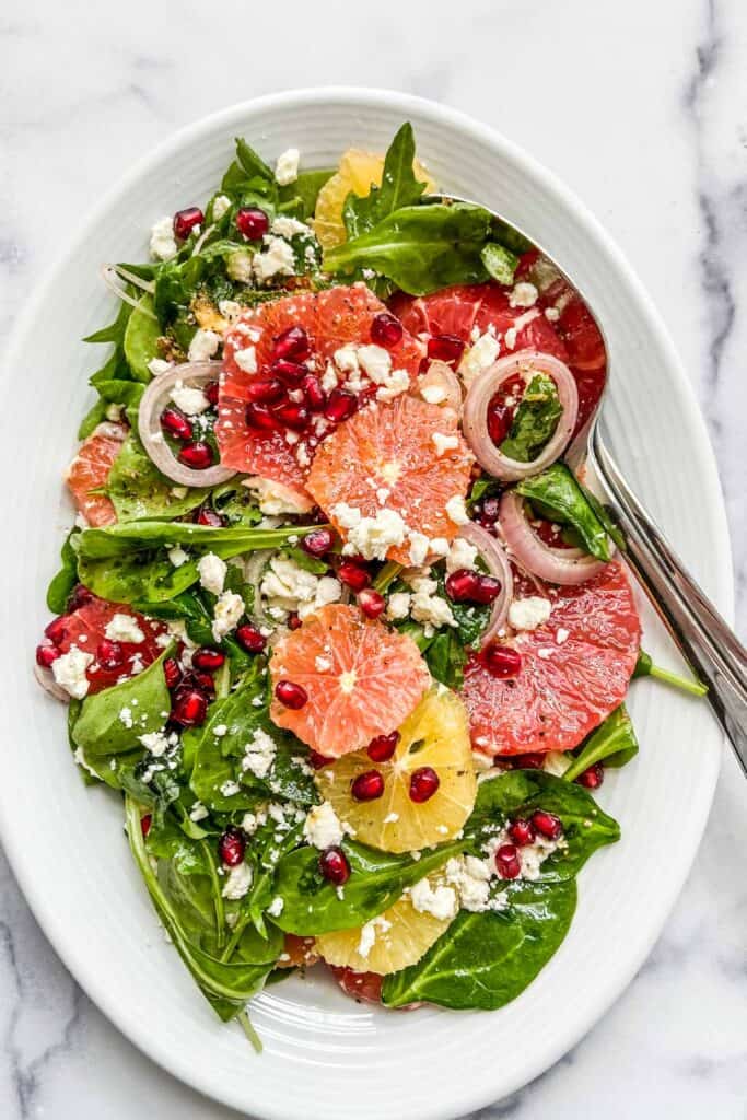 citrus pomegranate salad on a large serving dish with serving spoon