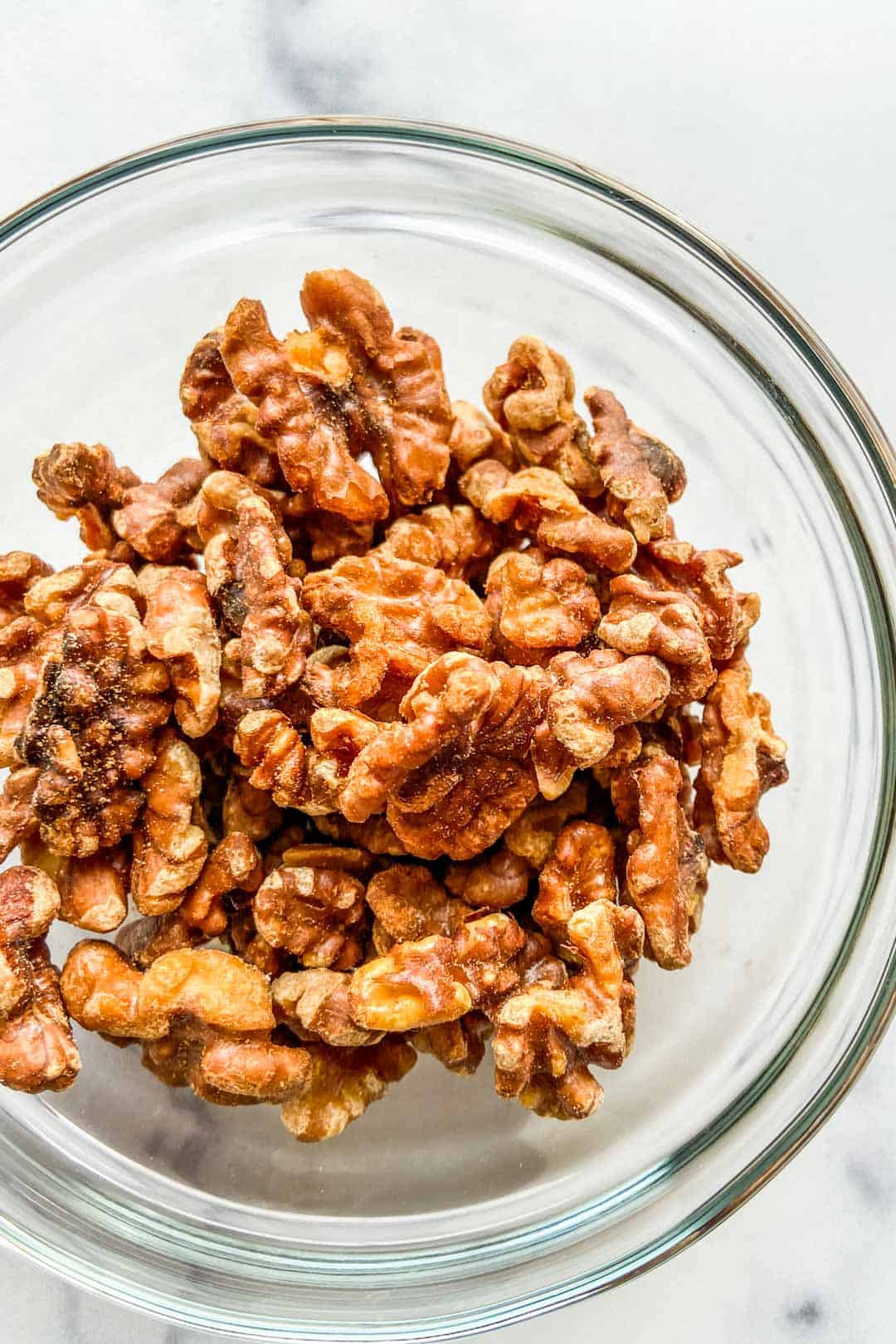closeup of toasted walnuts in a glass bowl