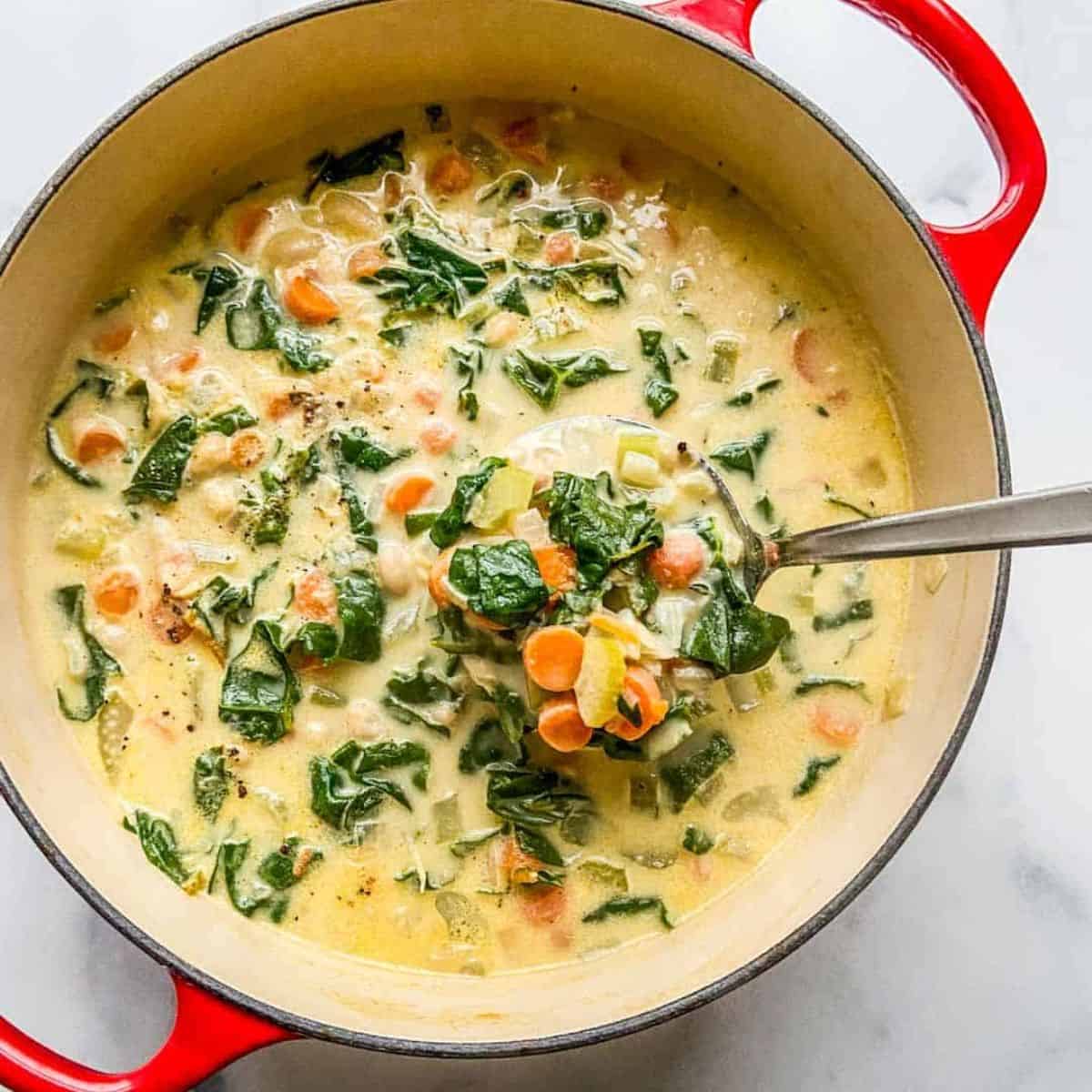 Creamy Tuscan white bean soup in a red dutch oven.